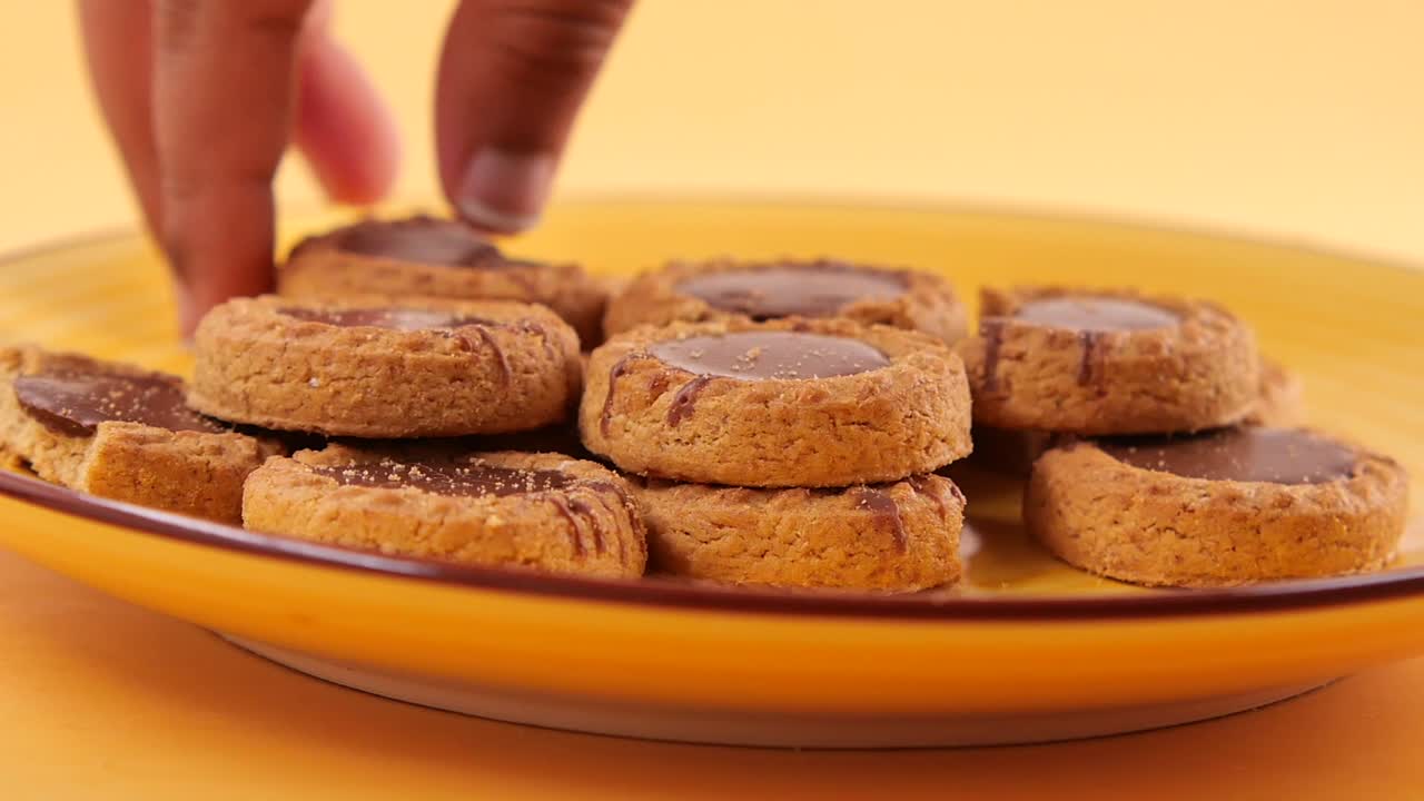 Hand Picking Up a Chocolate Cookie from a Plate