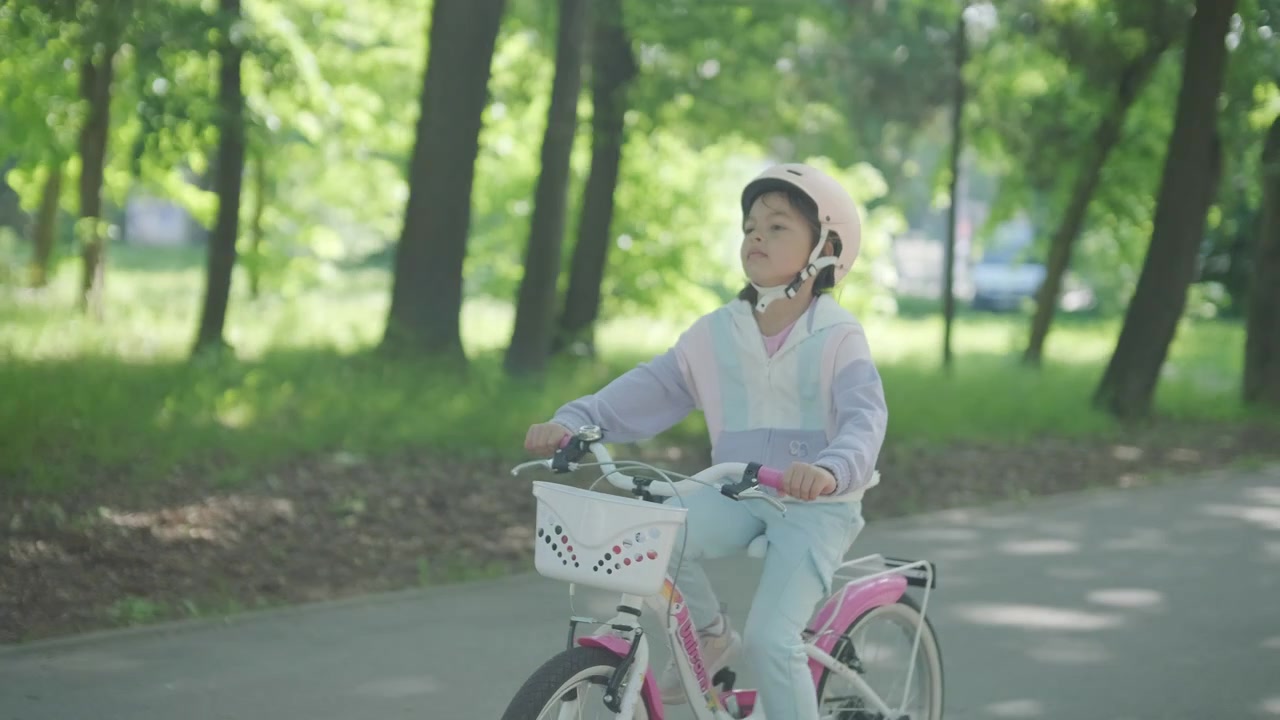 公園でヘルメットをかぶって自転車に乗る小さな女の子