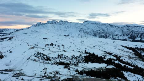 toma aérea panorámica de la cordillera en los dolomitas cubierta de nieve vista desde el prado alpino seiser alm - meseta alpe di siusi en tirol del sur, italia al atardecer