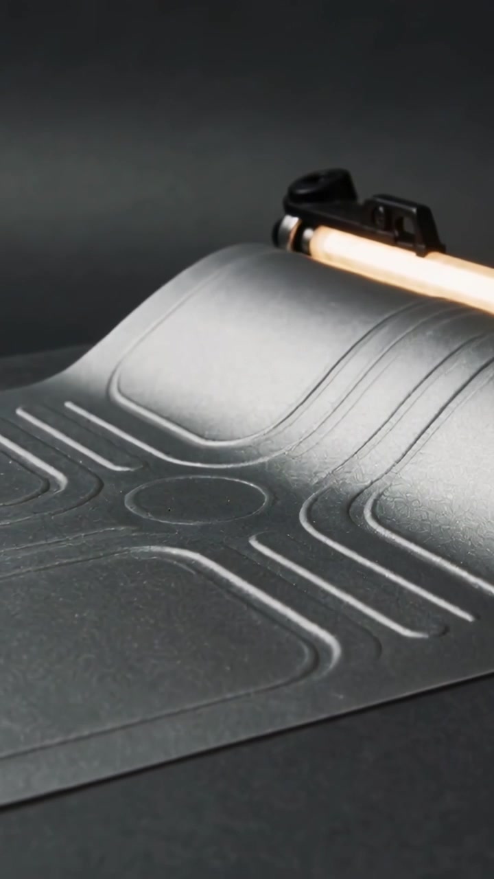 Vertical video: Lifting right edge, mat forming arch on table, revealing embossed grooves with tube