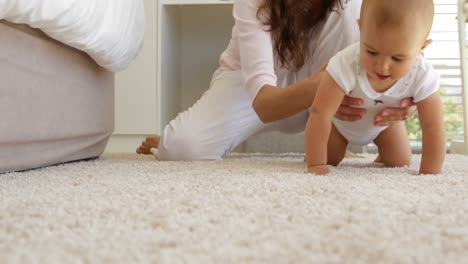 Mother-helping-her-baby-girl-crawl-away-on-the-rug