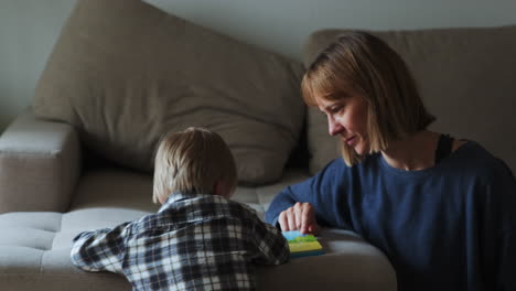 Young-boy-and-mother-reading-a-book-while-sitting-next-to-the-sofa