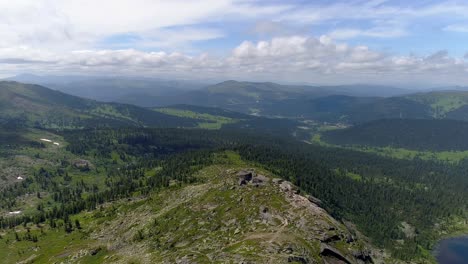 aerial view of a mountain range with a forest and a lake