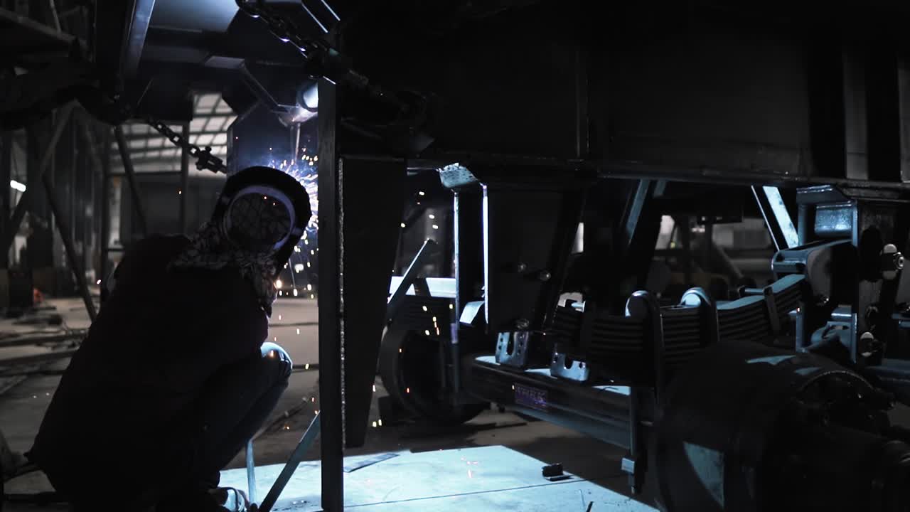 보호 장비를 착용하고 인도 공장 회사 생산 라인에서 트럭 트레일러의 철 부품을 용접하는 전문 노동자