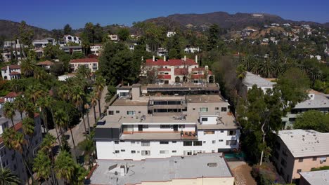 Reverse-pullback-aerial-shot-of-apartments-in-Hollywood-Hills-with-Highway-101-in-the-background-in-Los-Angeles,-California