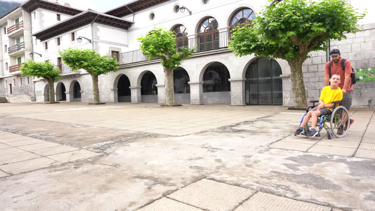 Man assists a child in a wheelchair in a public square