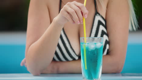 attractive woman drinking a cool cocktail on the side of the pool