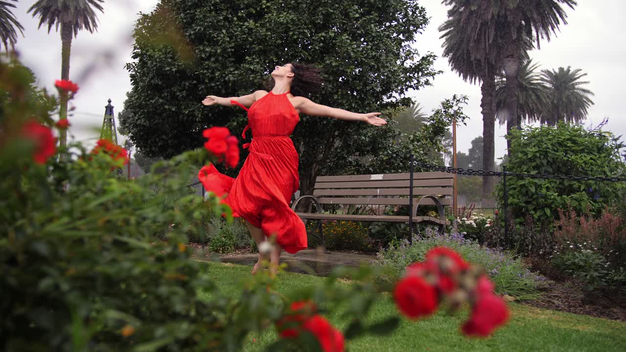 hermosa bailarina con vestido rojo dando vueltas y bailando en jardines de rosas