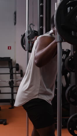 man performing barbell back squat in gym