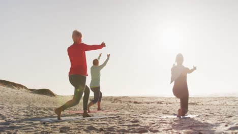 athletic women performing yoga in the beach