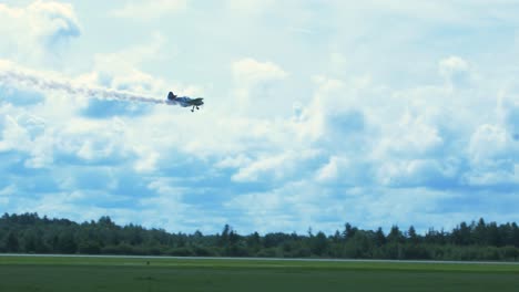 Sukhoi-Su-26-aerobatic-airplane-carrying-out-dynamic-maneuvers-in-front-of-spectators-at-Baltic-airshow-in-Liepaja,-Latvia,-white-smoke-trails,-handheld-tracking-shot,-4k