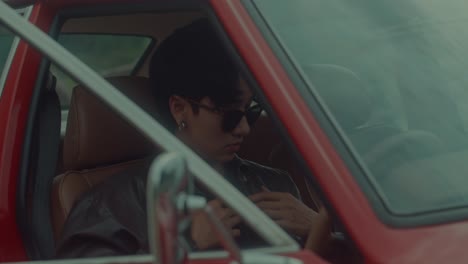 man driving a red vintage car