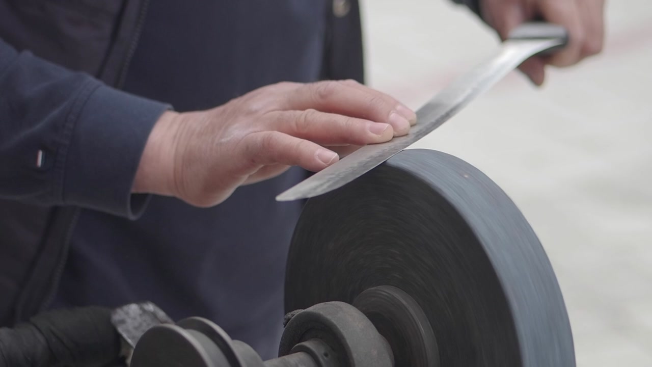 Close-up of a Craftsman Sharpening a Knife on a Grinding Wheel