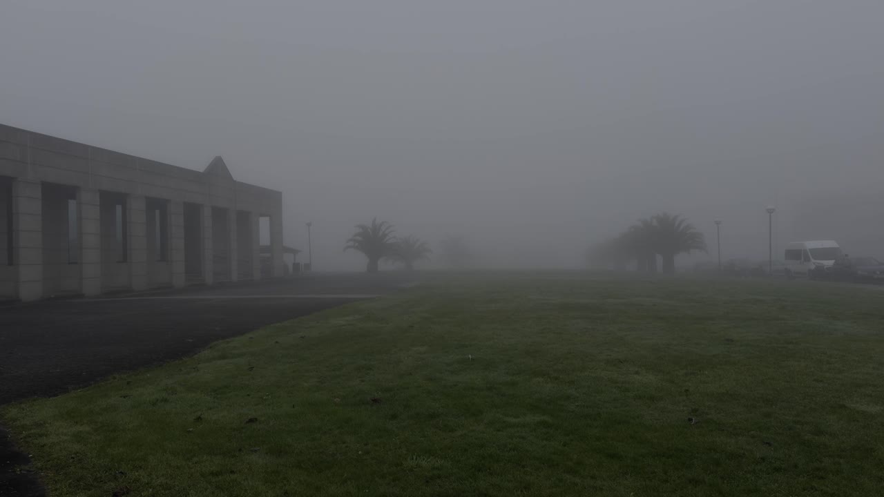 Spooky View Of A Green Field And A Modern Stone Building Covered In Fog