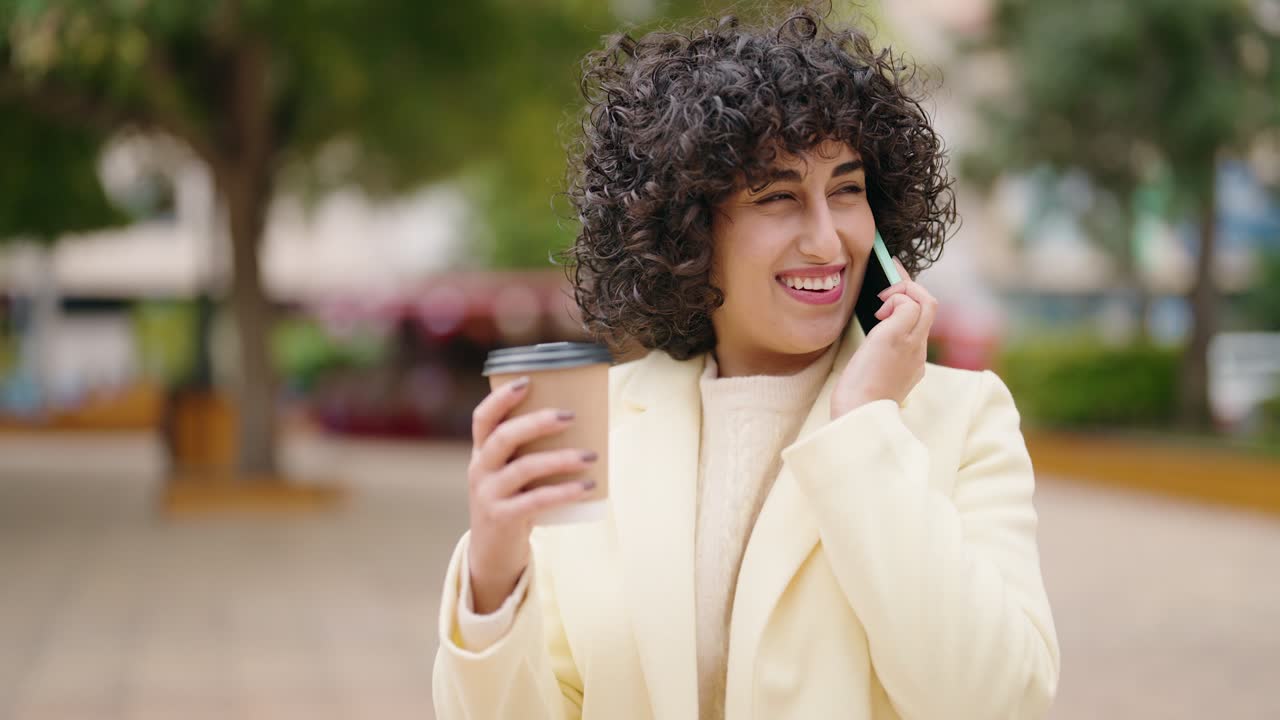 joven hablando en el teléfono inteligente bebiendo café en el parque
