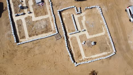 建筑工地上标记的住房基础的上升旋转空中视图,显示要建造的房子的明确定义足迹