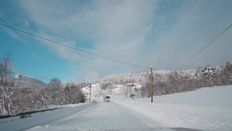 POV-Video-Einer-Fahrt-Bei-Tageslicht-Durch-Die-Verschneiten-Straßen-Der-Westlichen-Fjorde-Norwegens,-Umgeben-Von-Hohen,-Schneebedeckten-Bergen-Mit-Bäumen