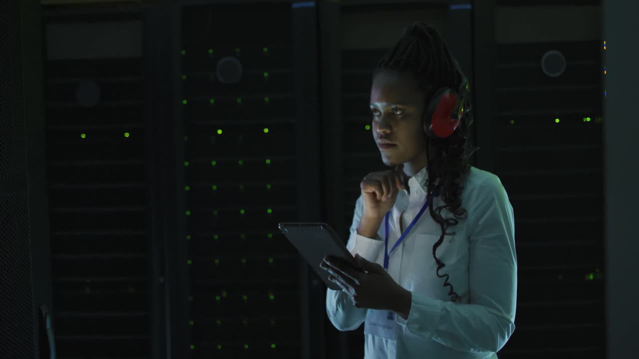 Afroamerikansk kvindelig computertekniker, der arbejder med en tablet i et serverrum.