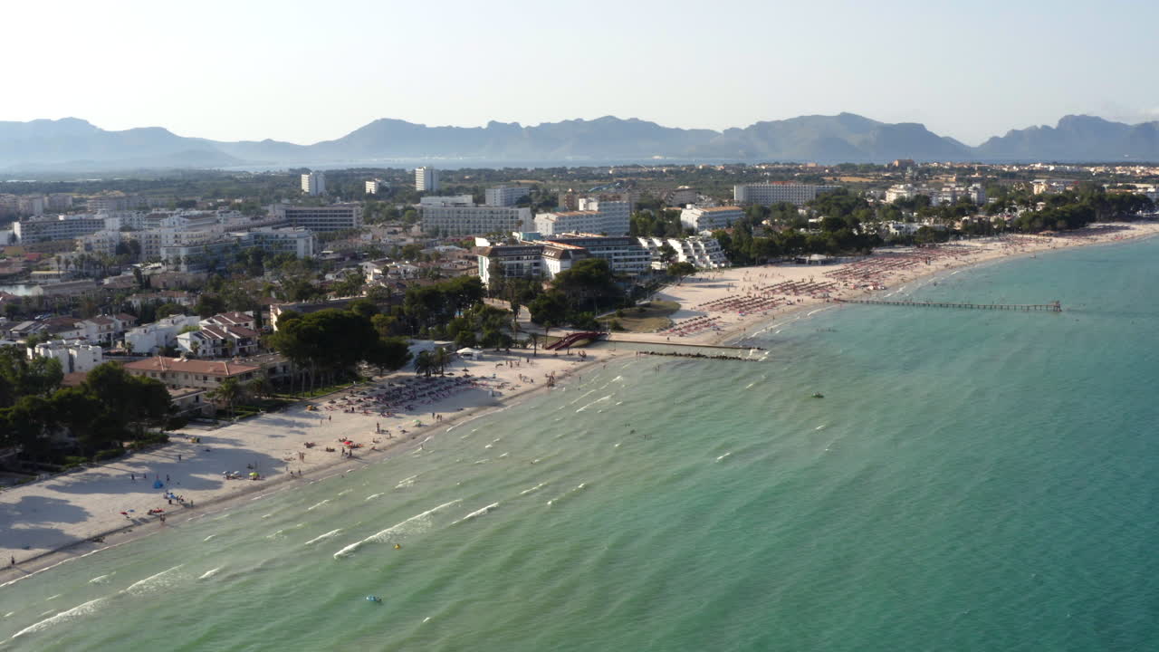las olas del mar bañando la playa con hoteles turísticos en alcudia