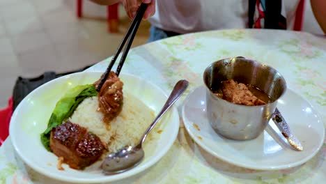 los palillos transfieren la carne de cerdo al plato de arroz