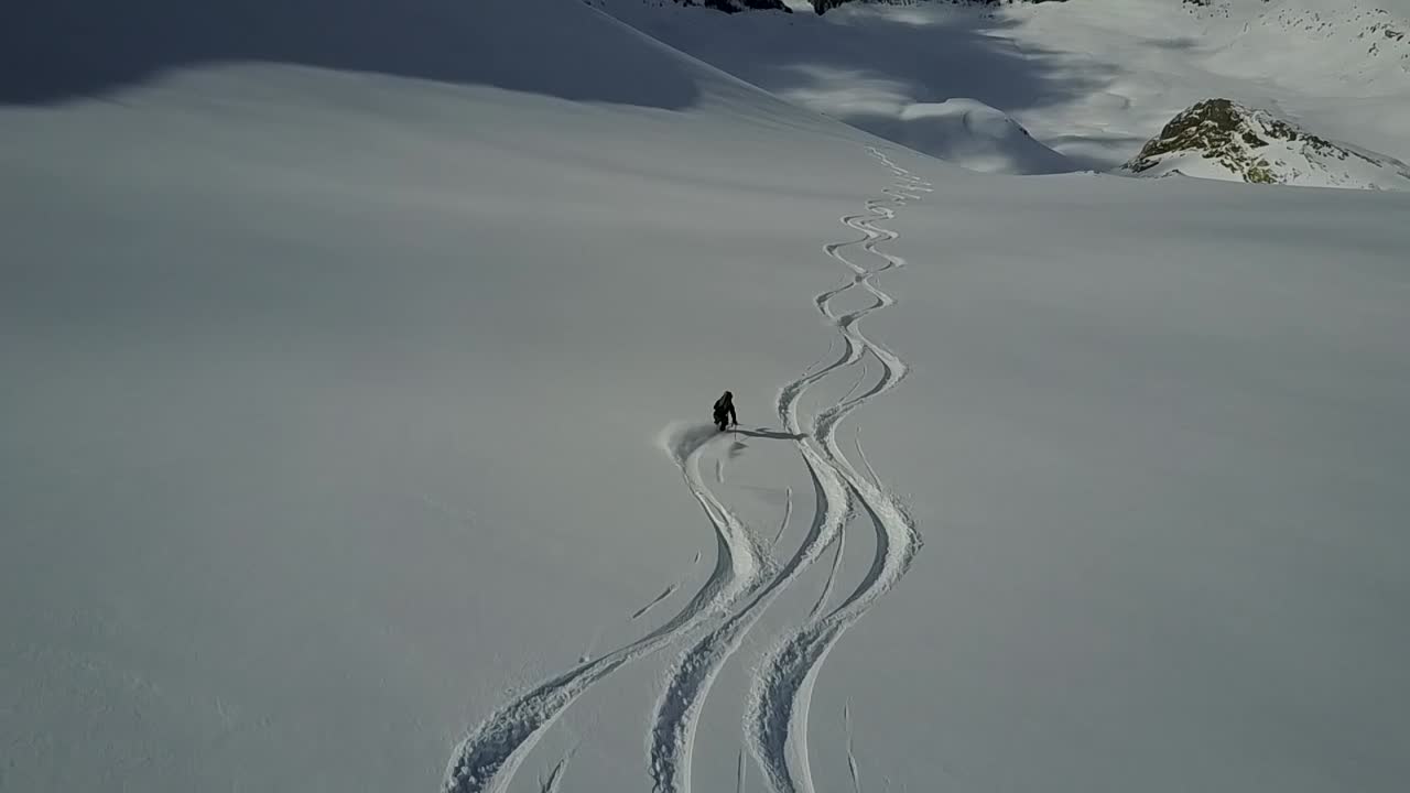 빈 파우더 슬로프를 내려가는 무인 항공기 추적 스키어