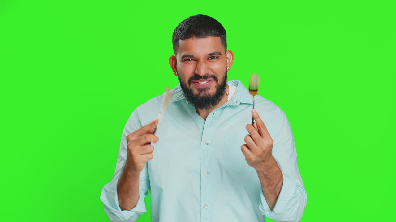 Hungry man waiting for serving dinner meal dishes with restlessness holding cutlery fork knife