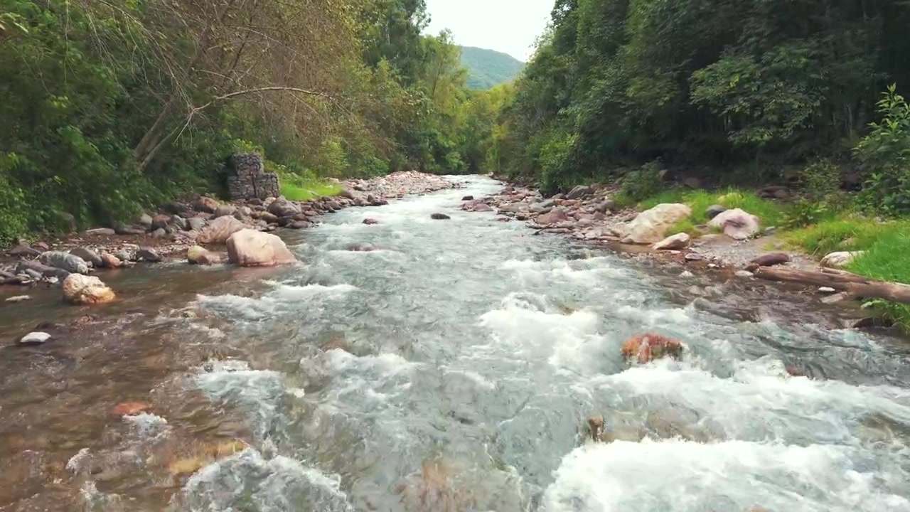 Un bellissimo fiume con acque cristalline che scorre tra un terreno roccioso, circondato da maestose montagne.