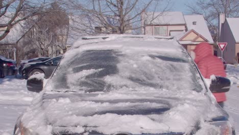 man in orange ski jacket brushes snow off his car timelapse