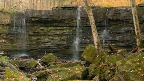 waterfall on majestic geological rock structure in autumn forest, static view