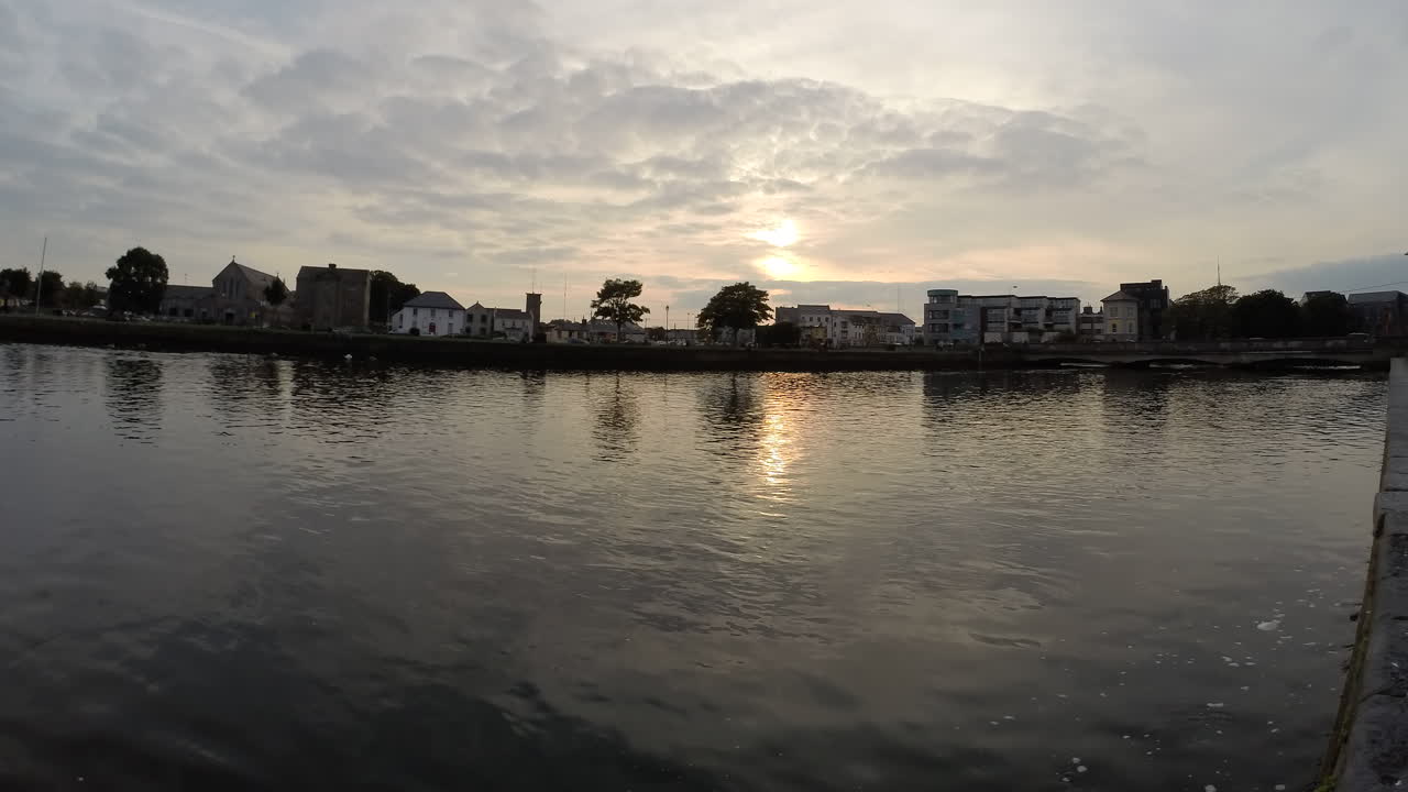 Timelapse panning over the Corrib River at sunset, capturing swans gliding through Galway city center
