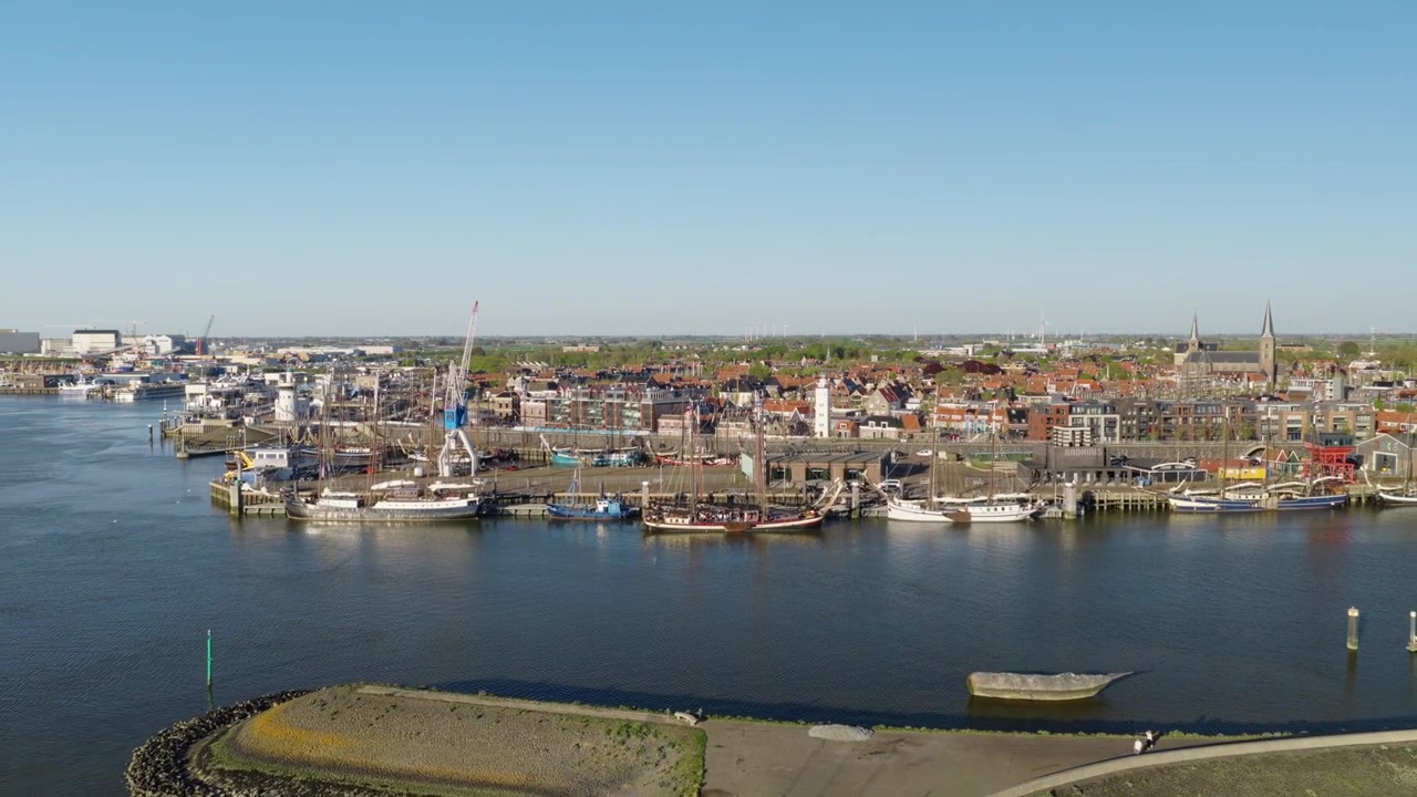 Harlingen Haven, Harlingen, Friesland, Nederland, met historische zeilschepen, jachthavenplaatsen, pakhuizen aan het water, kerktorens en de Waddenzee haven, drone-uitzoomen.