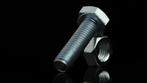 close-up of a metal bolt and nut on a reflective black surface