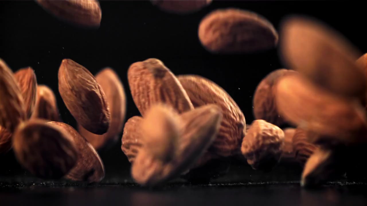 Almonds Falling and Bouncing in Slow Motion on Black Background