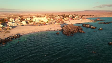 Aerial-descending-shot-of-waves-crashing-on-Bahia-Inglesa-beach-during-sunset