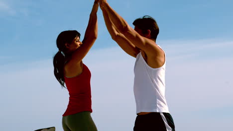 una pareja feliz dando los cinco en la playa.