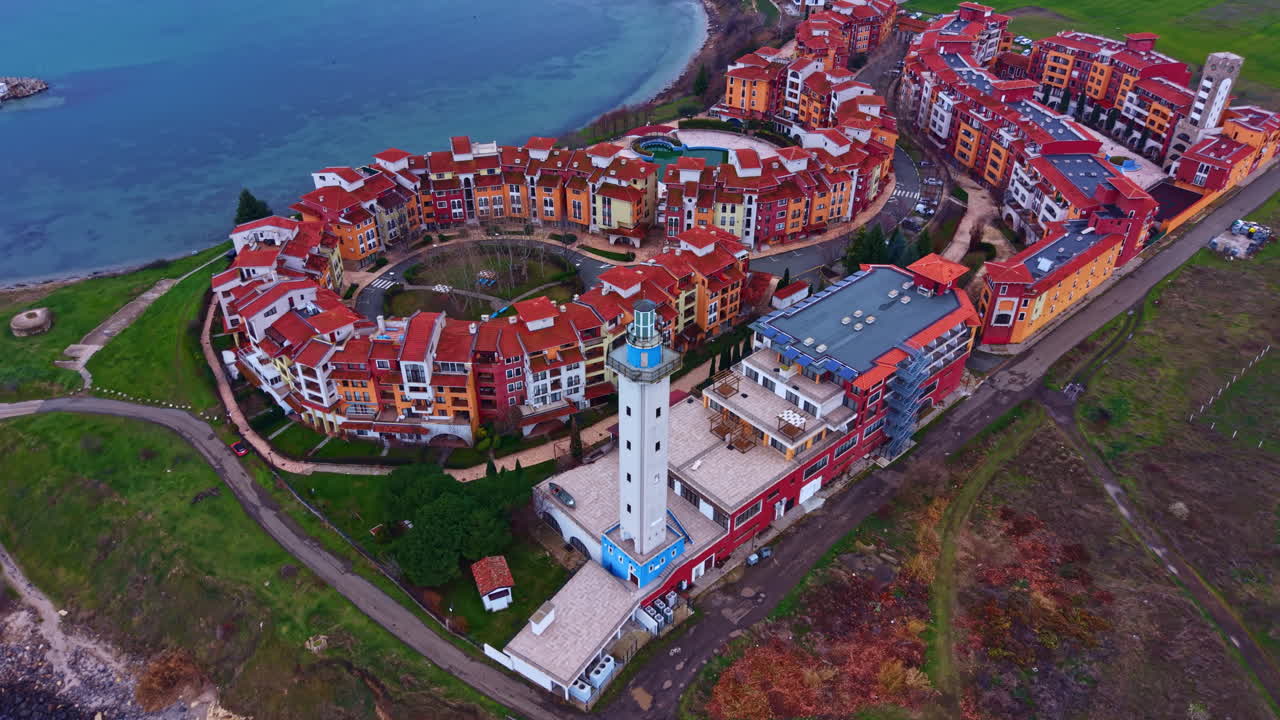 Vista di una località turistica costiera con edifici circolari e un faro, situata vicino all'acqua durante le ore diurne