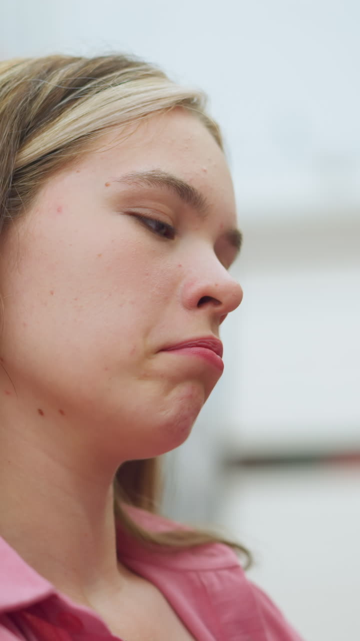 dama en vestido rosa desabrochado en una tienda asente pensativamente, con una expresión contemplativa en un centro comercial, mientras está de pie en un entorno bien iluminado, los elementos de fondo están ligeramente borrosos