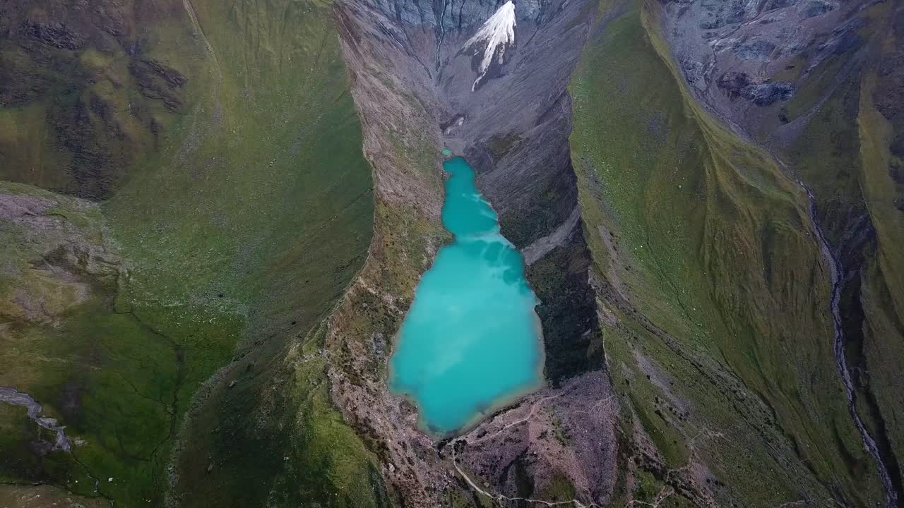 Aerial, reverse, drone shot overlooking laguna Humantay lake, in Andes mountains, cloudy day, in Cusco region, Peru