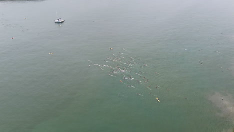 Vista-Aérea-De-Personas-Irreconocibles-Nadando-Y-Compitiendo-En-Un-Triatlón,-Volando-Sobre-La-Competencia-Al-Aire-Libre