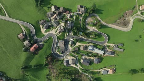 static overhead footage of the winding road cutting through the la val village in the italian dolomites mountains