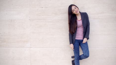 trendy young woman posing against a wall