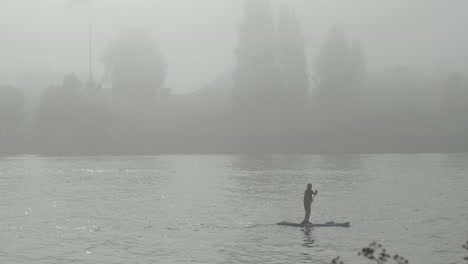 man on paddleboard moving in intense fog