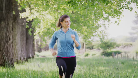 crane shot of woman exercising running through countryside field