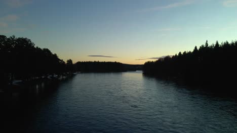 Sunrise-Yellow-Sky-at-River-Surrounded-by-Forest,-Rising-Aerial