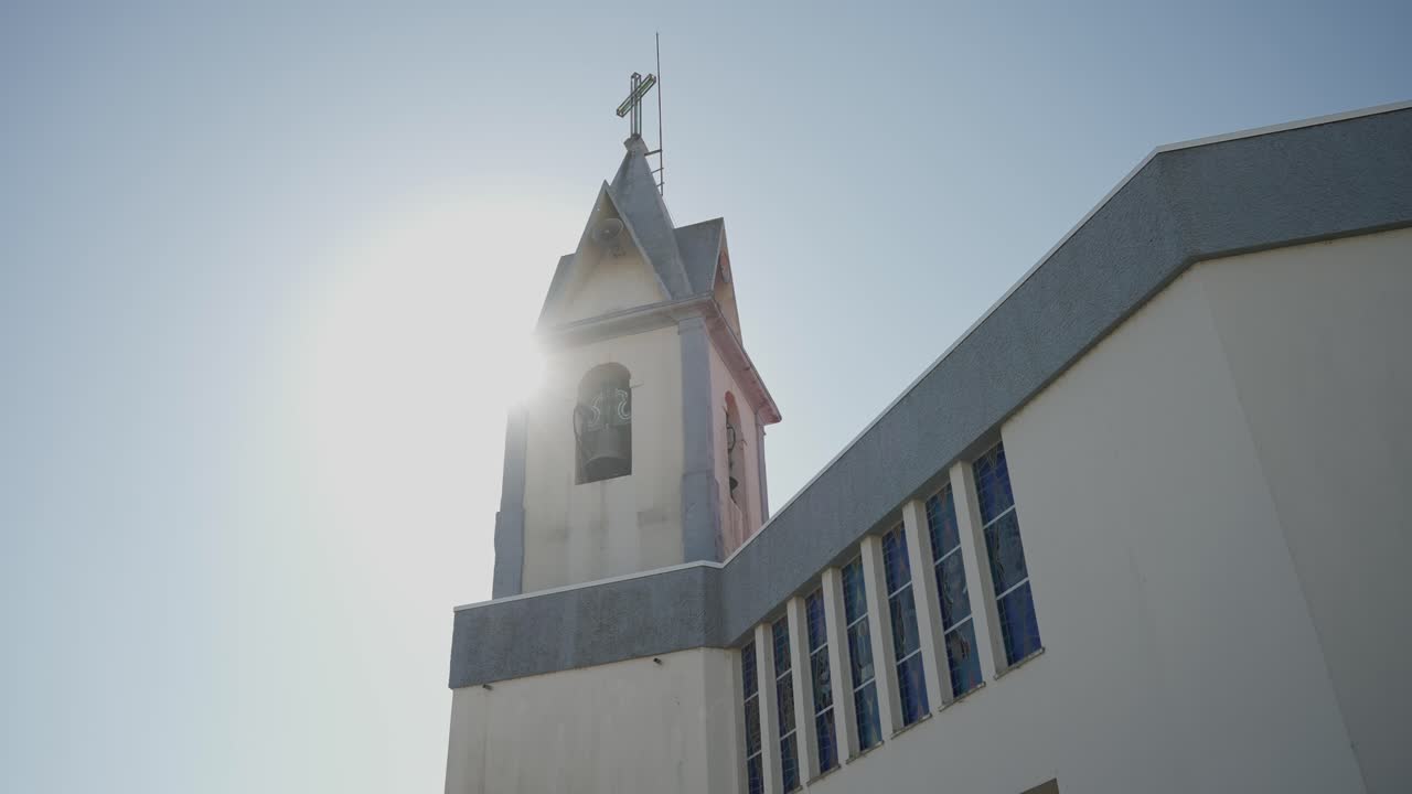 Il sole splende dietro il campanile della chiesa con la croce