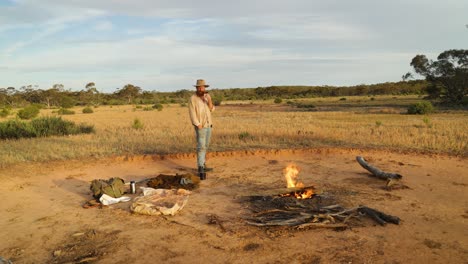 a swagman smokes a pipe by a campfire in the australian outback