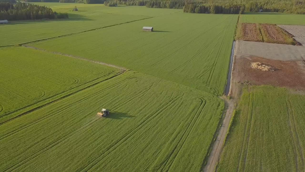 esparciendo fertilizante con tractor en un campo verde al atardecer earial 4k