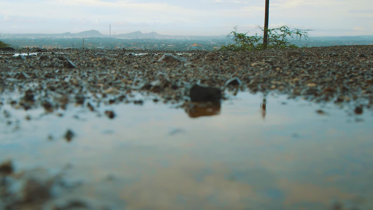 Rain causes of Puddle in the road of Curacao With Beautiful Landscape in the Background - Close up Shot