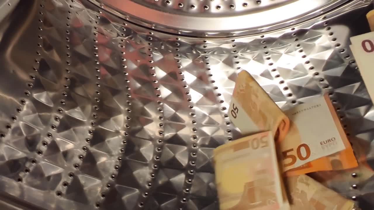 Euro banknotes being washed in a steel washing machine in slow motion