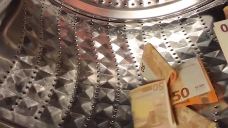 euro banknotes being washed in a steel washing machine in slow motion